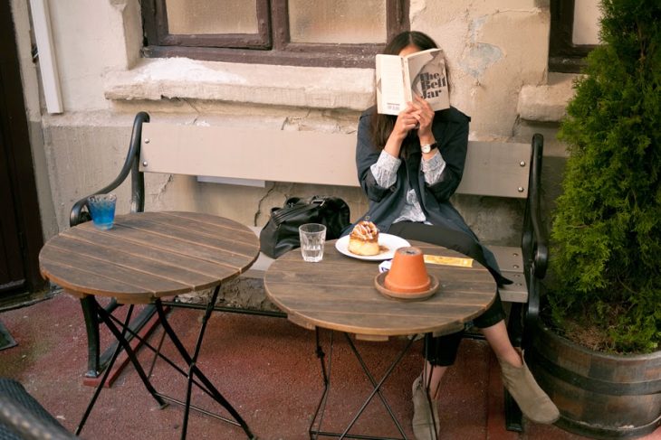 Chica sentada en una banca leyendo 