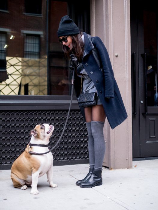 Mujer con medias y abrigo hablando con su perro bulldog