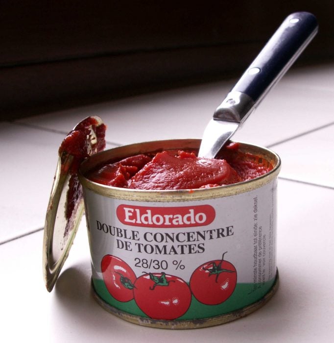 cuchara sacando tomates de una lata 