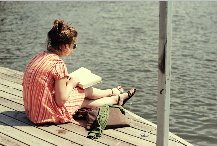 mujer sentada en un muelle leyendo