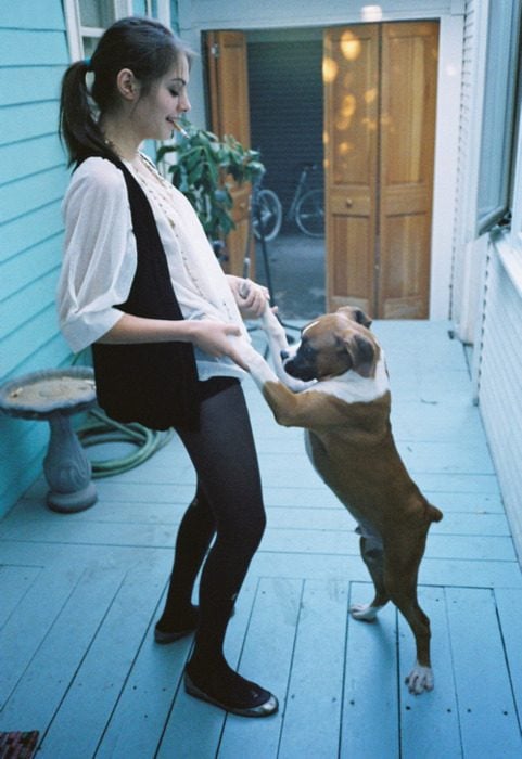 chica con un cigarrillo bailando con su perro boxer 