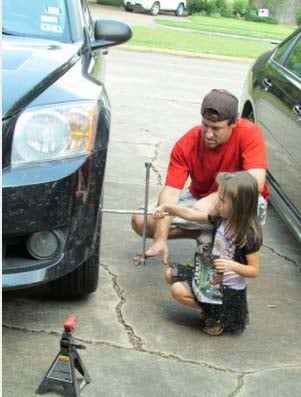 padre enseñandole a su hija a cambiar una llanta 