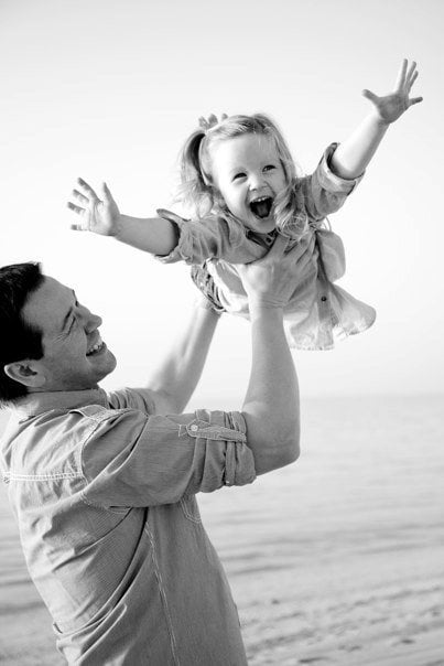 papá jugando con una niña en la playa 
