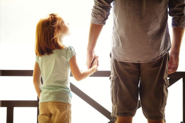 hombre tomando de la mano a su hija pequeña 