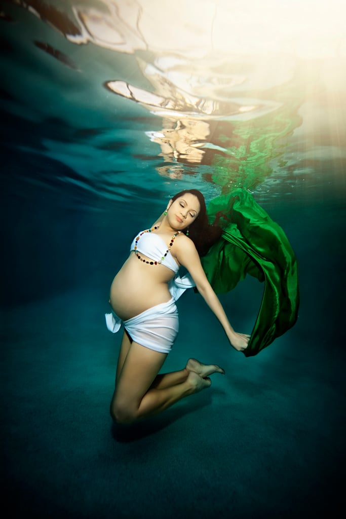 embarazada con traje de baño blanco sosteniendo una tela verde bajo el agua