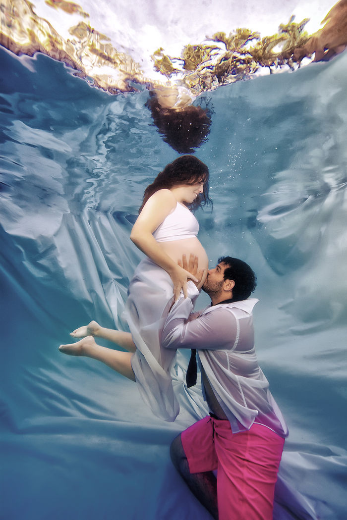 hombre besando el vientre de su esposa bajo el agua 