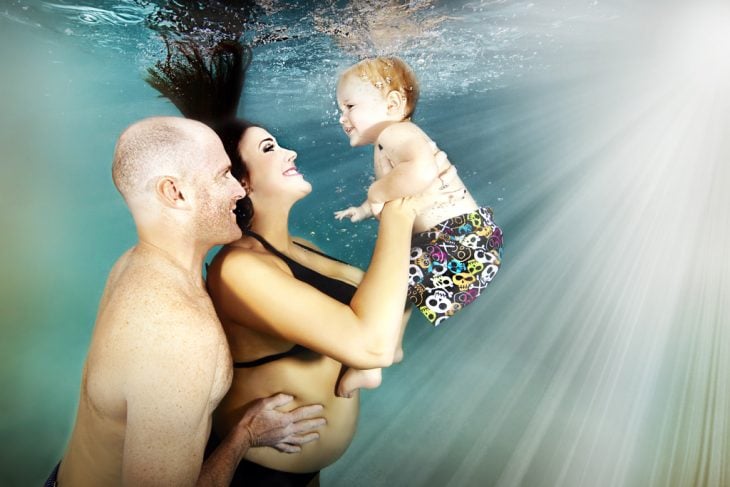 pareja sosteniendo a un bebe bajo el agua 