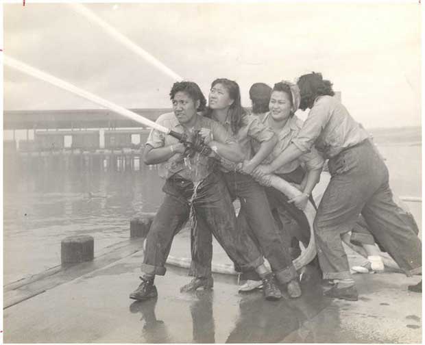 mujeres sosteniendo una manguera de bomberos apagando un incendio 