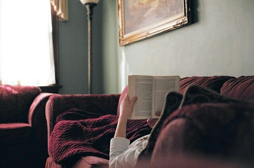 chica acostada en un sofÃ¡ leyendo un libro 