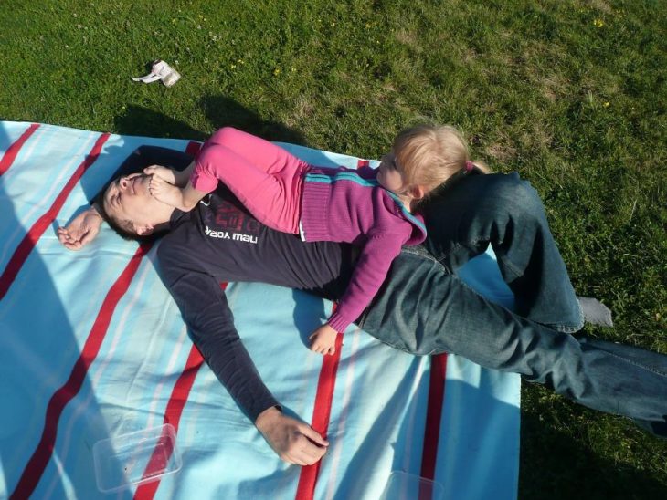 niña dormida sobre las piernas de su padre en un jardín 