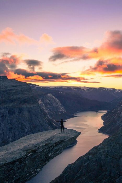 hombre parado en una montaña viendo el atardecer 