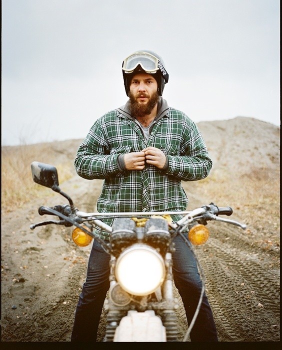 hombre con barba usando una chamarra verde en una motocicleta