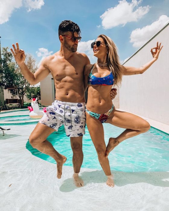 pareja haciendo pose de yoga frente a una alberca