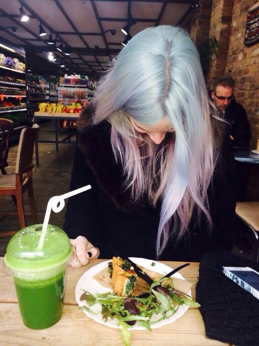 chica de cabello plateado comiendo comida vegetariana 