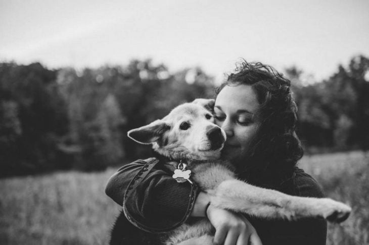 Foto en blanco y negro de un perro y su dueña abrazados 