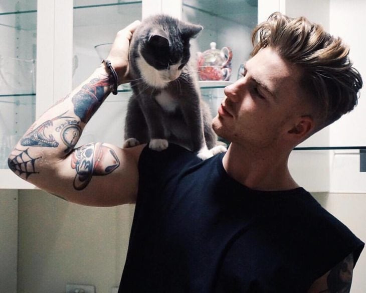 Hombre tatuado cargando a un gato