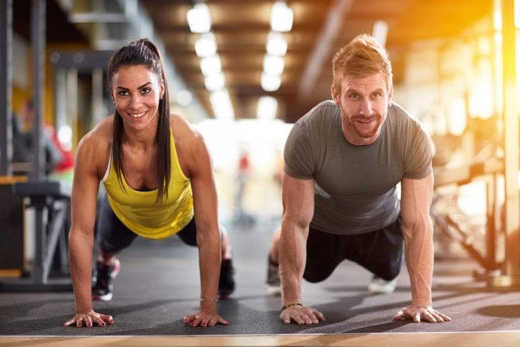 Pareja de novios haciendo ejercicio en las maquinas de un gimnasio 