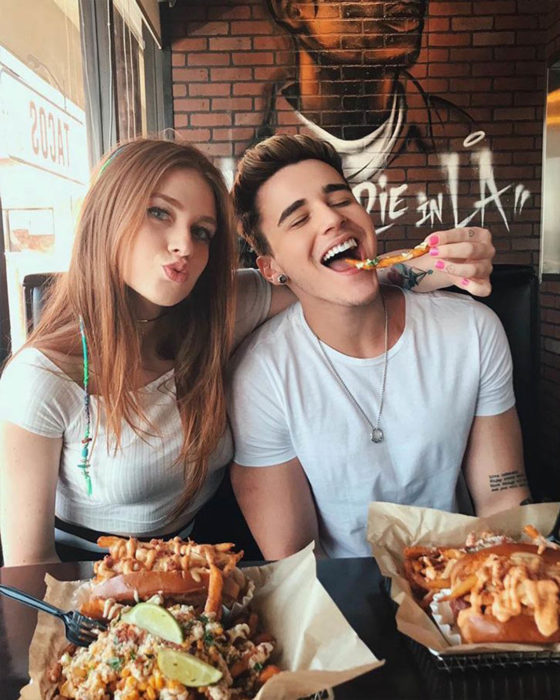 Pareja de novios en un restaurante comiendo papas fritas y pizza 