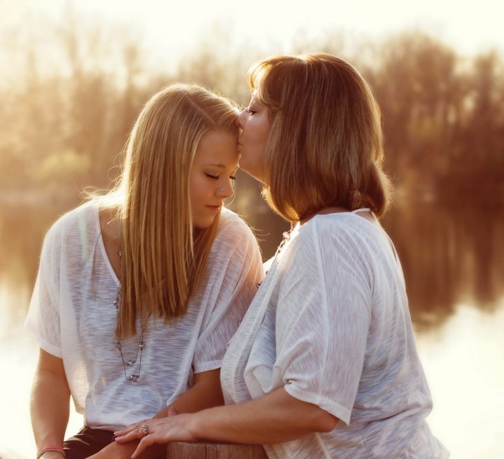 Foto de madre e hija a la orilla de un lago al atardecer 