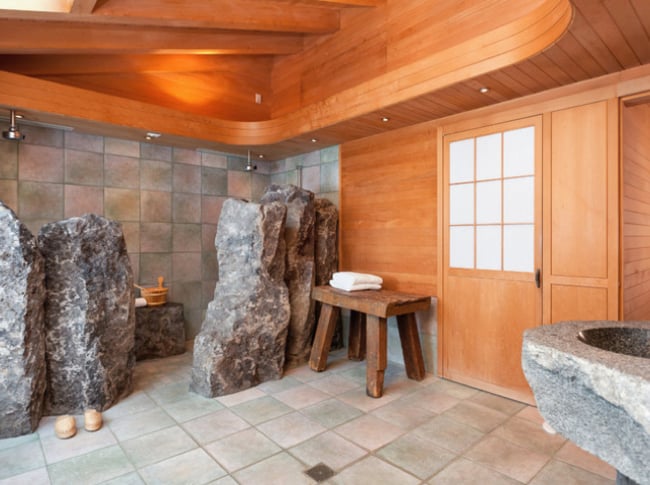 baño con diseños en piedra y paredes de madera 