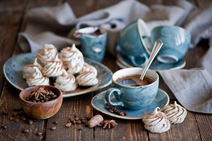 el olor del cafe en una taza de ceramica azul con panecillos 