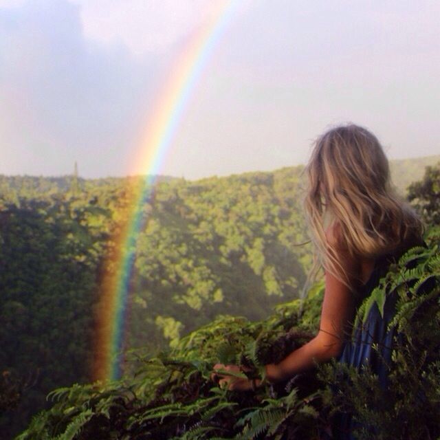 chica sentada en la selva observando un arcoiris 