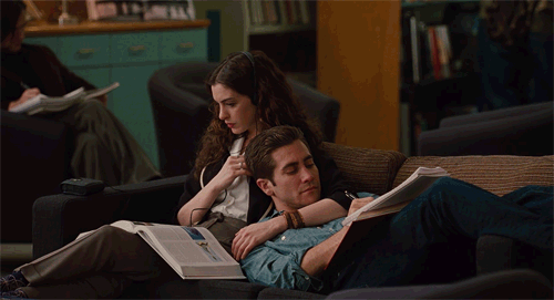 pareja sentada en un sofá leyendo un libro y escuchando música 