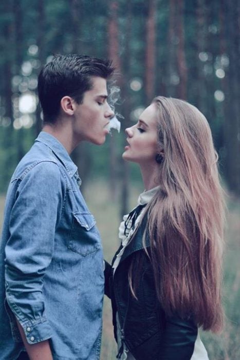 pareja de novios en medio de un bosque fumando 
