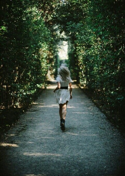 chica de cabello platinado corriendo en medio de un bosque 