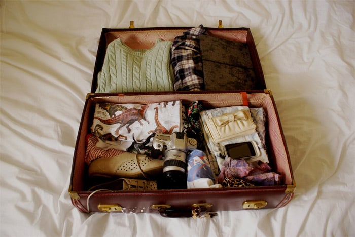 maleta abierta con ropa y una cámara en su interior 
