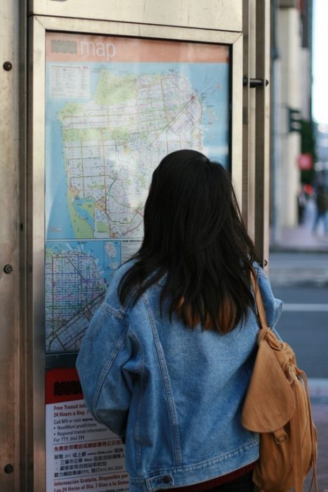 chica de cabello negro viendo un mapa en una pared 