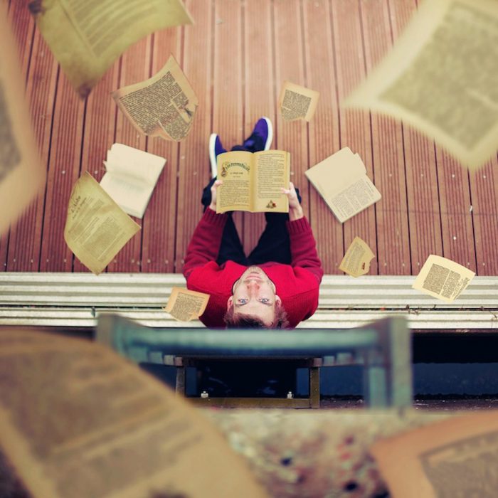 Chico vestido de rojo con un libro en las manos mirando para arriba 