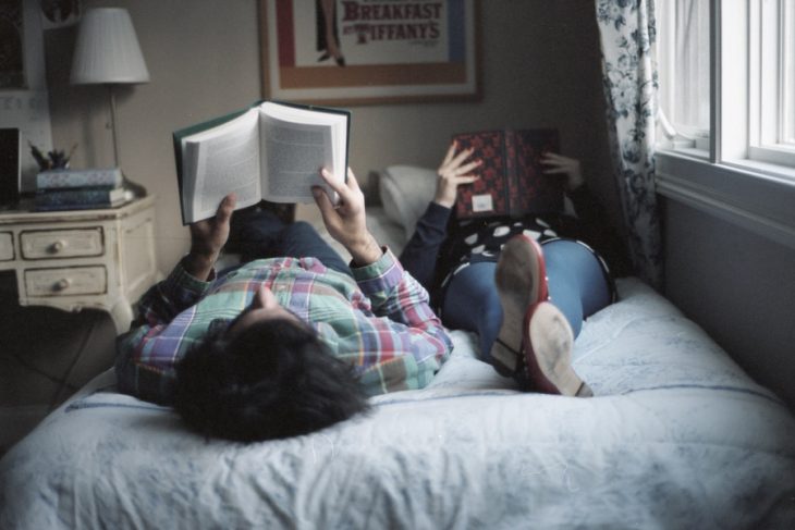 Pareja de novios en la cama leyendo un libro 