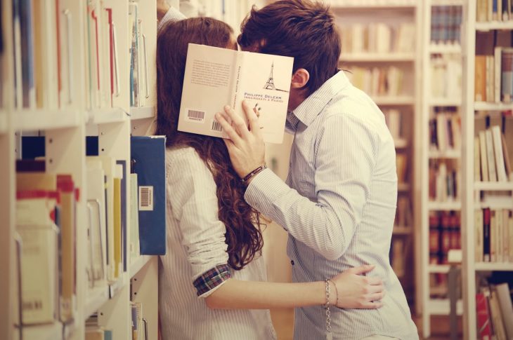 pareja de novios besándose en una biblioteca 