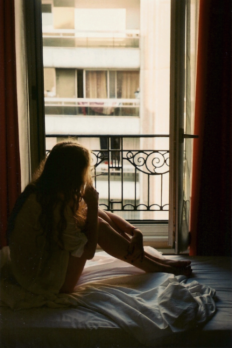 Chica observando por la ventana de su habitación 