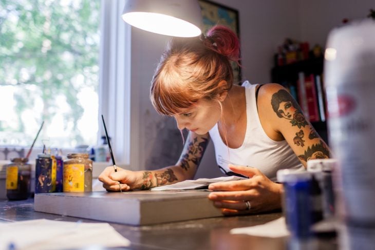 Chica con tatuajes pintando 