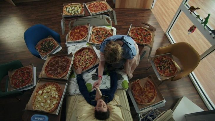 niño recostado en la cama rodeado de pizza 