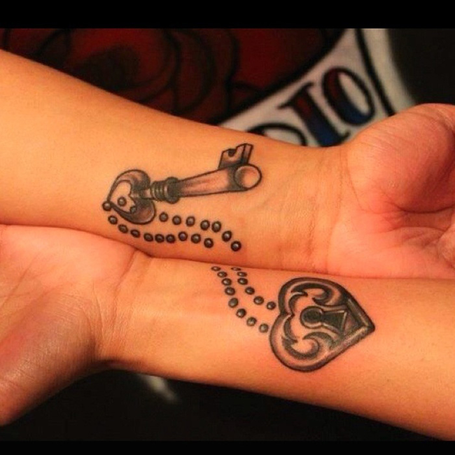 Bazos de una pareja mostrando en sus muñecas sus tatuajes en forma de cadena y corazón 