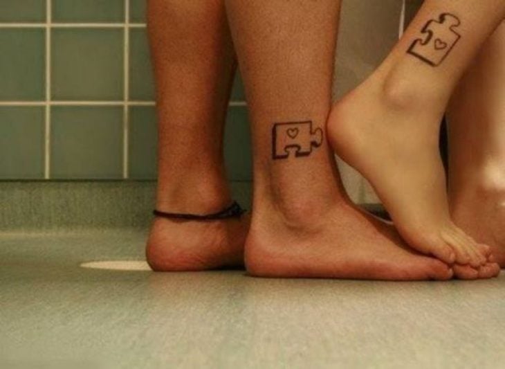 pareja mostrando sus pies con tatuajes en forma de piezas de puzzle 