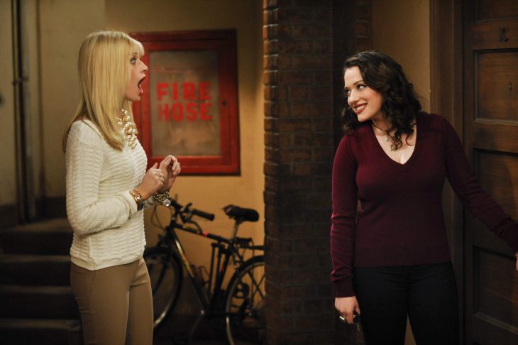 escena de la serie two broke girls la protagonista esta sorprendida tratando de abrir la puerta de su departamento 