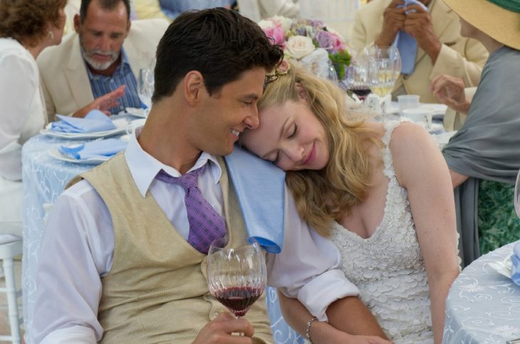 pareja de novios sentados abrazados bebiendo una copa de vino 