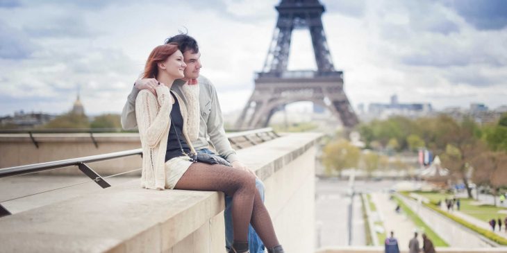 pareja de novios sentados en una barda viendo la ciudad 