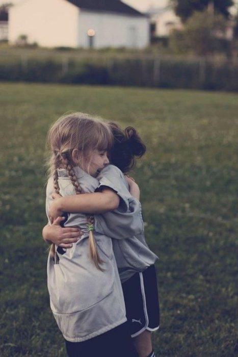 niñas abrazándose en un campo de fútbol 