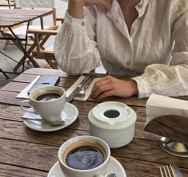 Manos de una mujer sentada en una mesa frente al café