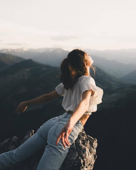 Mujer en la cima de una montaña con la cara al sol