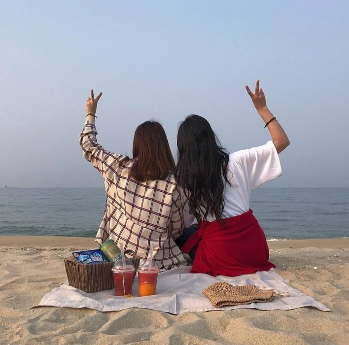 chicas sentadas en la arena haciendo un picnic