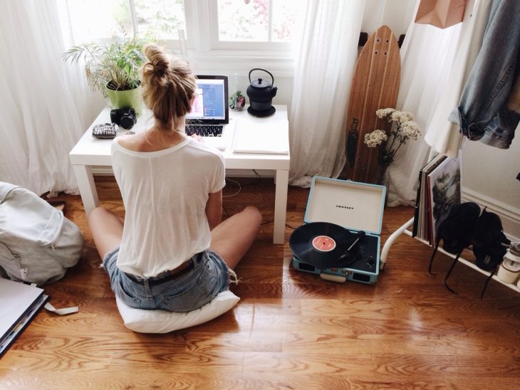 Chica sentada en el piso frente a una computadora 