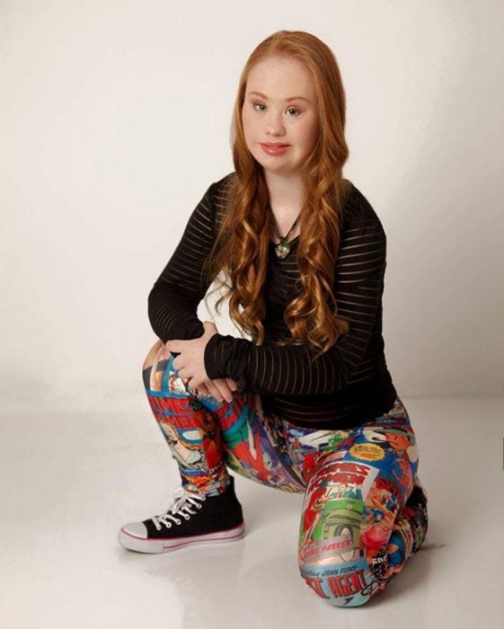 chica con síndrome de Down usando unas mallas de colores y un suéter negro 