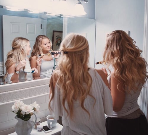 chicas frente al espejo planchandose el cabello 
