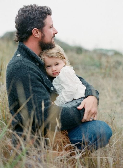padre e hija abrazados en un campo 